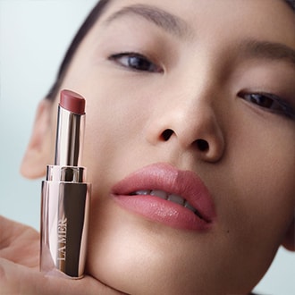 Close up of model applying serum to cheek, smiling